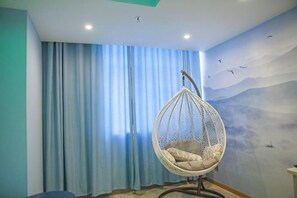 Ein Zimmer mit Hängekorbschaukel, großem Fenster mit Vorhängen und Wandgemälde.