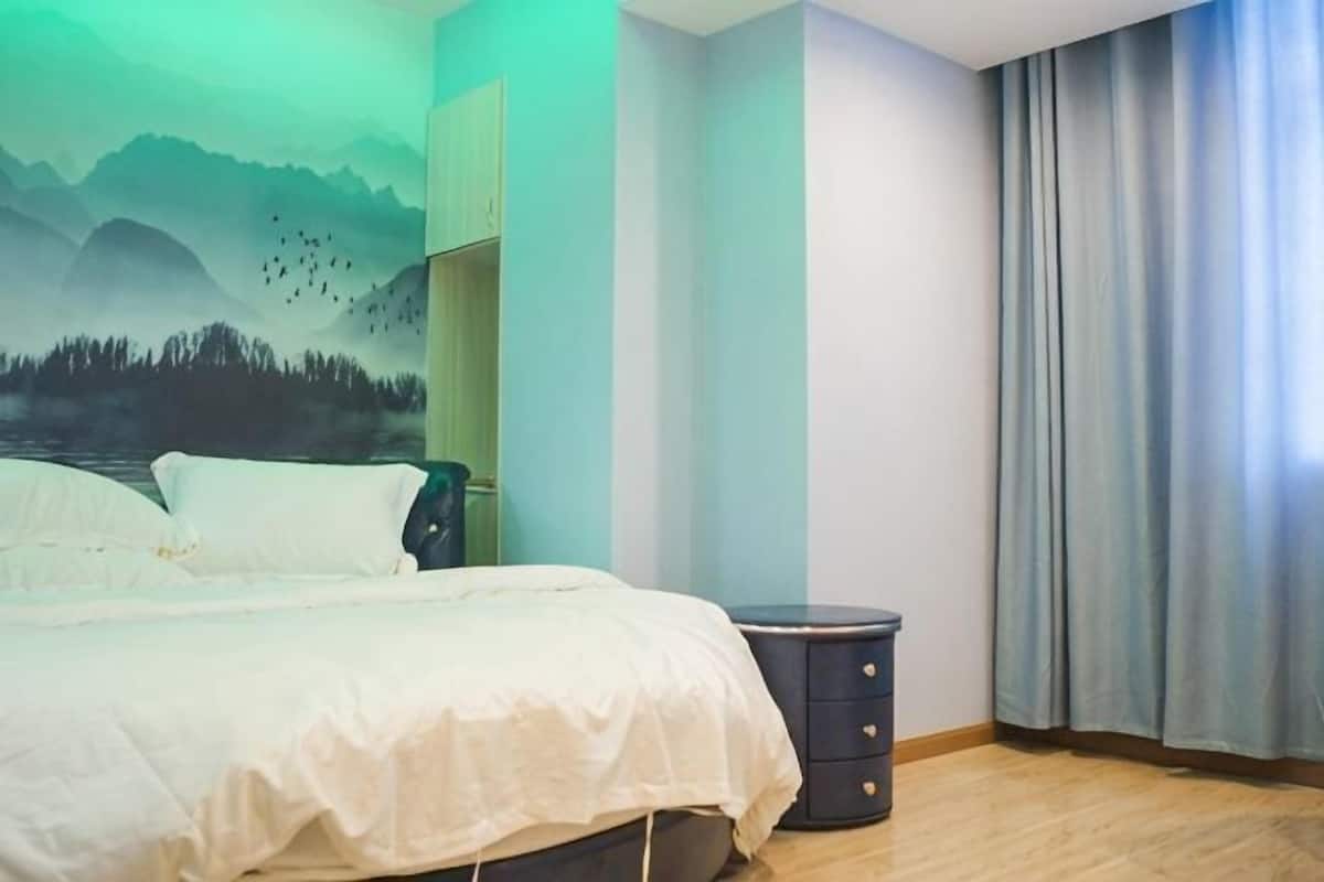 Un dormitorio con cama, cómoda, un mural en la pared y una ventana con cortinas.