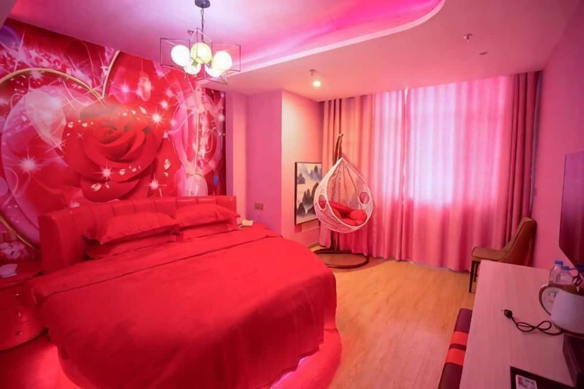 Un dormitorio con una cama grande, una silla colgante y un escritorio con una silla.