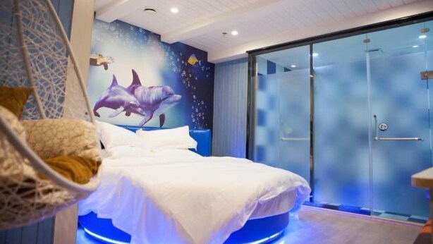 Un dormitorio con cama, cabina de ducha de vidrio y un mural de delfines.