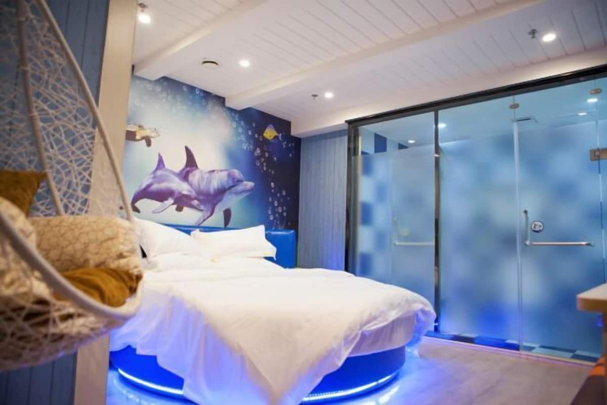 Un dormitorio con cama, cabina de ducha de vidrio y un mural de delfines.