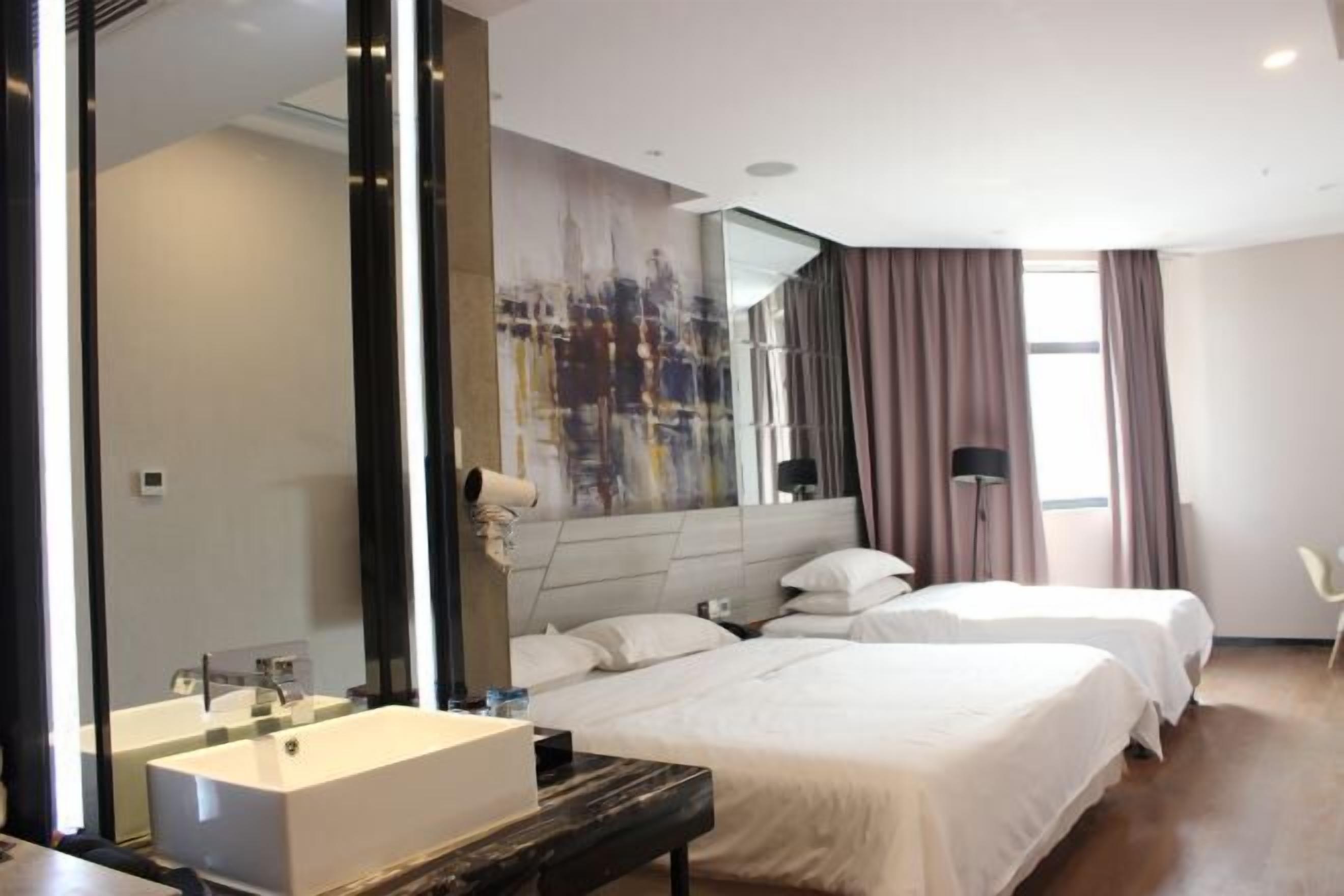 A hotel room with a large mirror, a modern bathroom, two beds, and a large window with curtains.