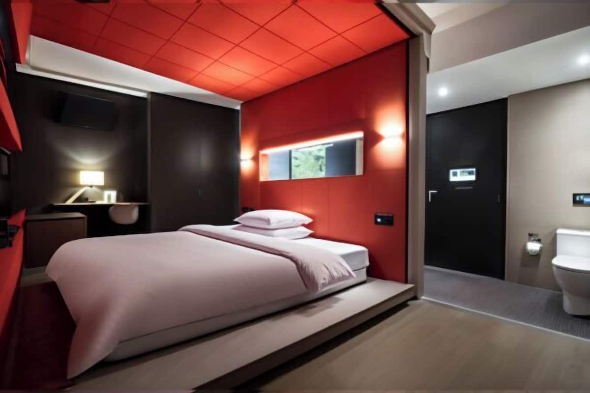 Moderni hotellihuone, jossa on sänky, televisio, työpöytä ja kylpyhuone.