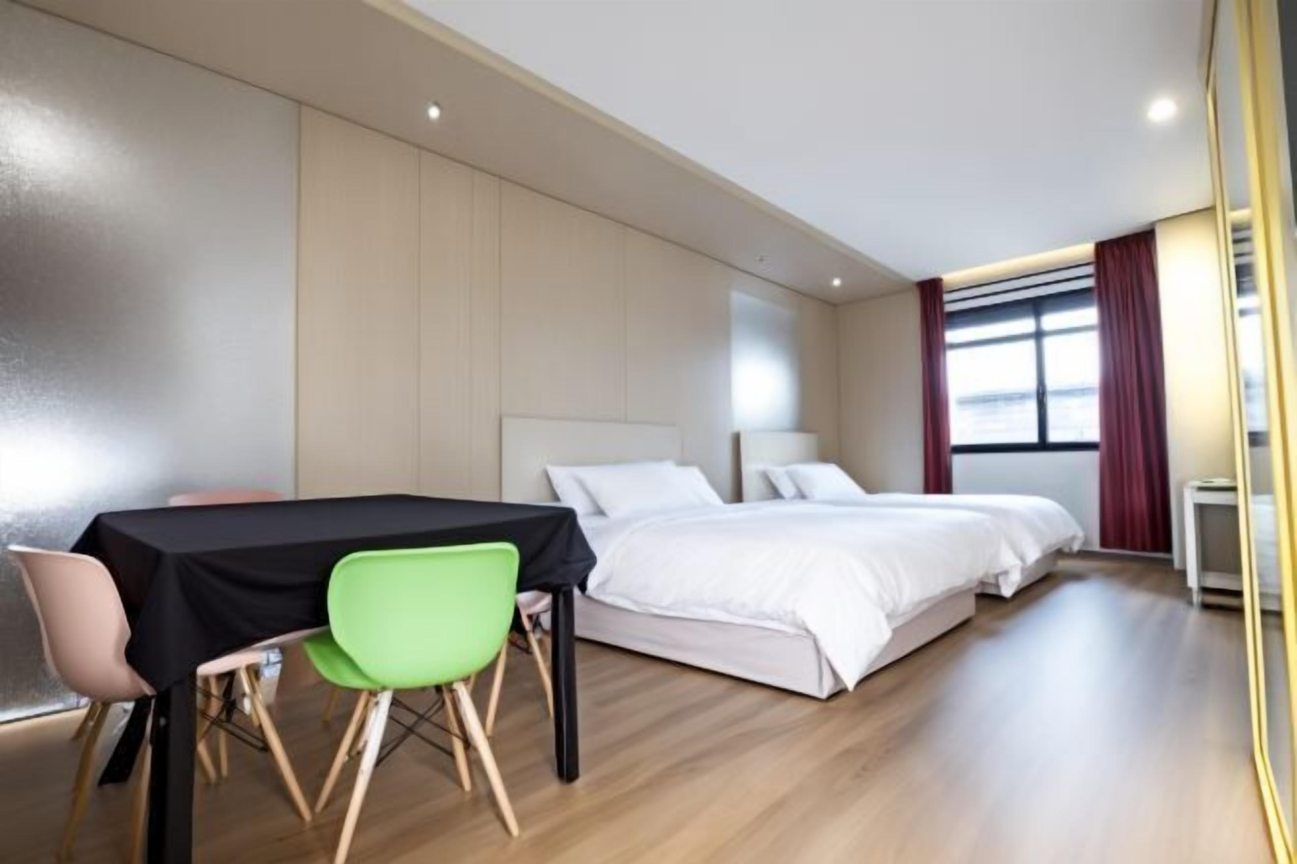 A hotel room with a bed, a table with chairs, and a window with curtains.
