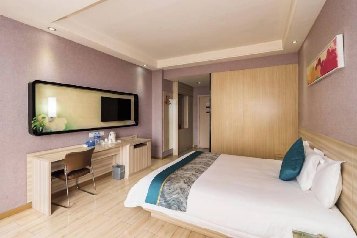 Habitació d'hotel amb llit, escriptori, cadira, televisió i armari.