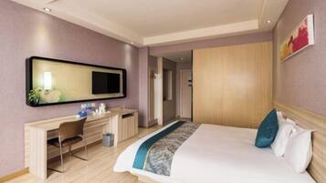 A hotel room with a bed, a desk, a chair, a TV, and a wardrobe.