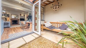 A cozy patio with a wooden bench, a fireplace, and a dining area. - Norfolk House, Heacham, Norfolk (Heacham)