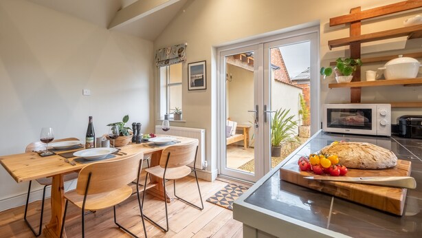 A modern kitchen with wooden furniture, a dining area, and a view to the outside. - Norfolk House, Heacham, Norfolk (Heacham)