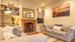 A cozy living room with a fireplace, two sofas, a coffee table, and a bookshelf. - Norfolk House, Heacham, Norfolk (Heacham)