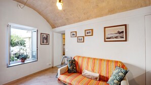 Ein Zimmer mit einer Couch, einem Fenster mit Blick und mehreren gerahmten Bildern an der Wand.