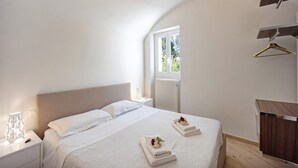 Ein Schlafzimmer mit einem Bett, Nachttischen, einem Fenster und einer Holzkommode.