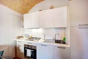 A compact kitchen with white cabinetry, a gas stove, a sink, and a built-in oven.