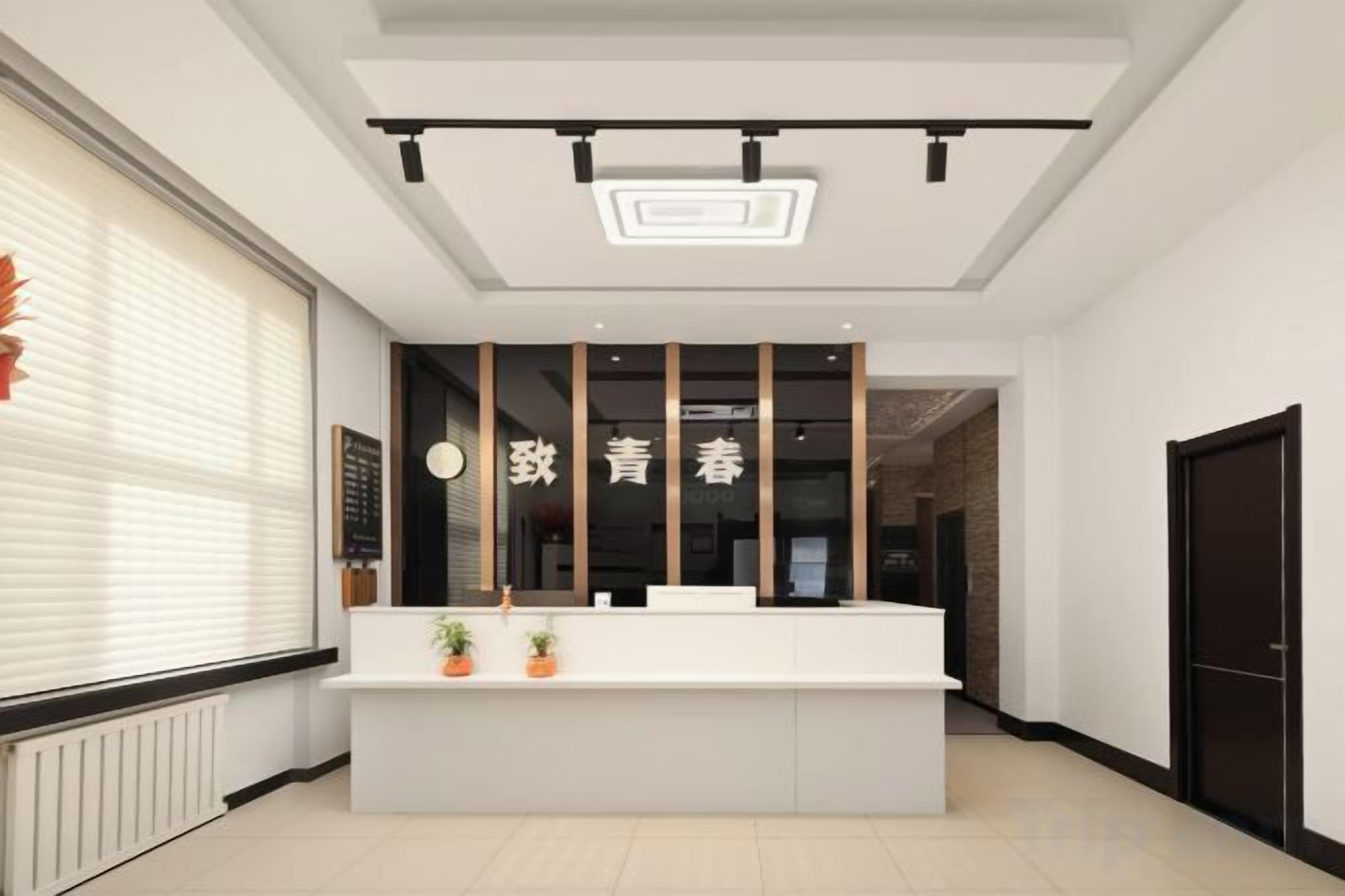 A reception desk with a modern design, a large window with blinds, and a door to the right.
