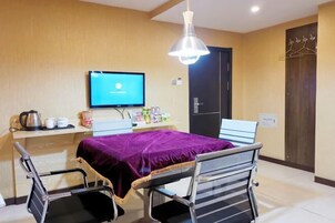Una habitación de hotel con una cama, un escritorio con computadora, una silla y un televisor.