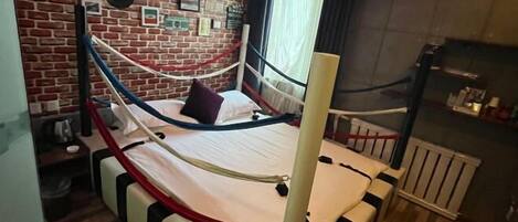 Una habitación con una cama, una pared de ladrillo y una ventana.