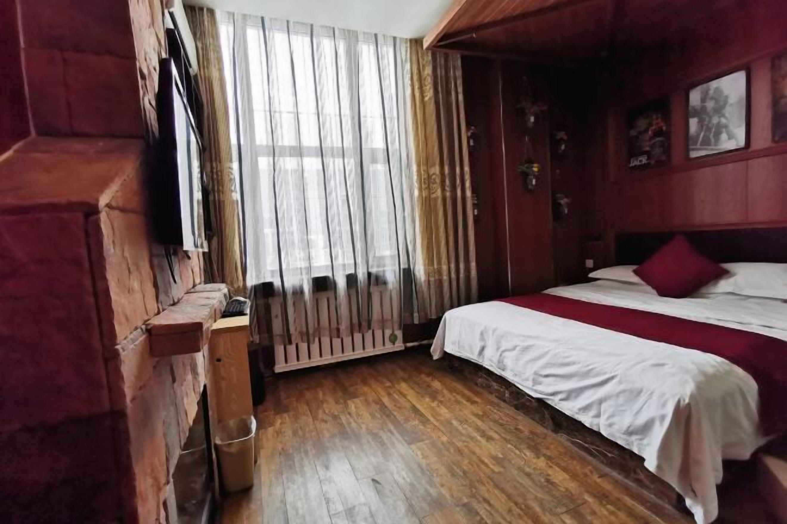 A wooden-framed room with a bed, a radiator, and a window with curtains.
