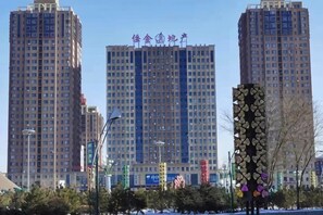A cityscape with tall buildings, one with a sign in a foreign language, and a decorative structure in the foreground. - Zhiyoung Theme Hotel (Daqing Xinbaida Dongfeng Middle School) (Daqing)