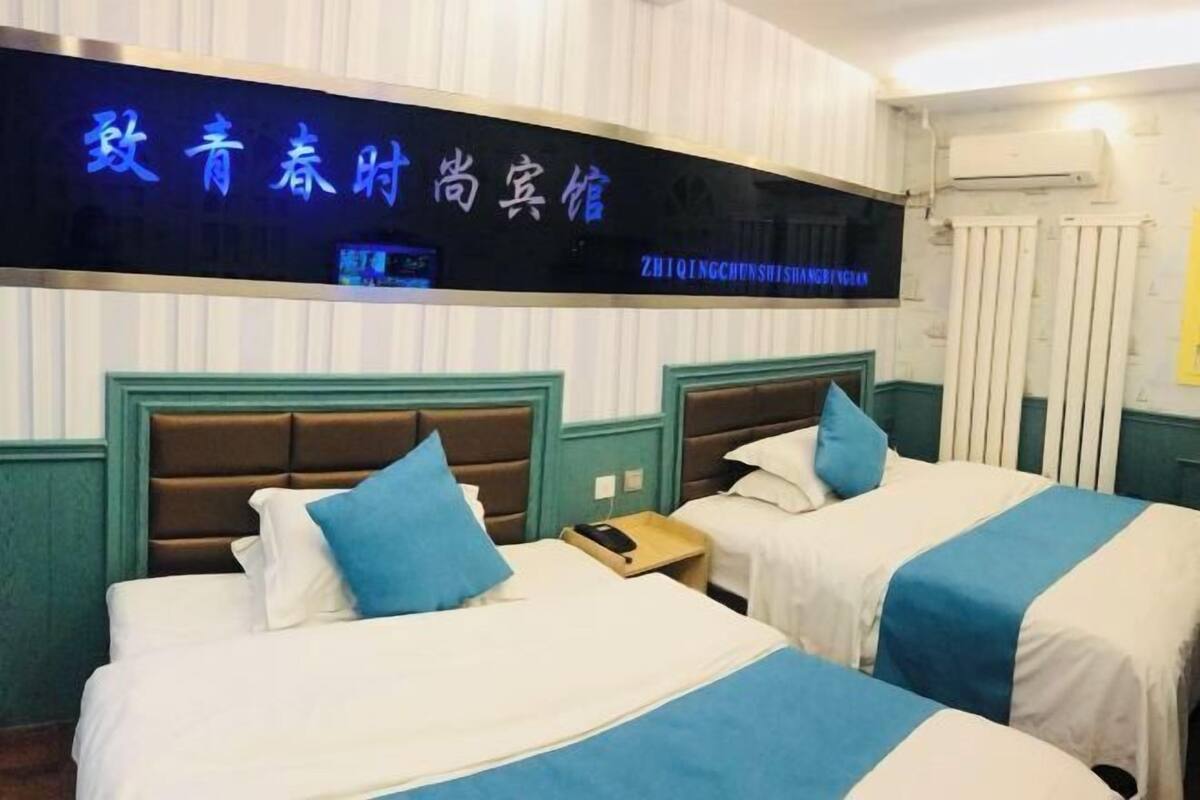 Une chambre d’hôtel avec deux lits, chacun doté d’une tête de lit, d’une table de chevet et d’un téléviseur fixé au mur.