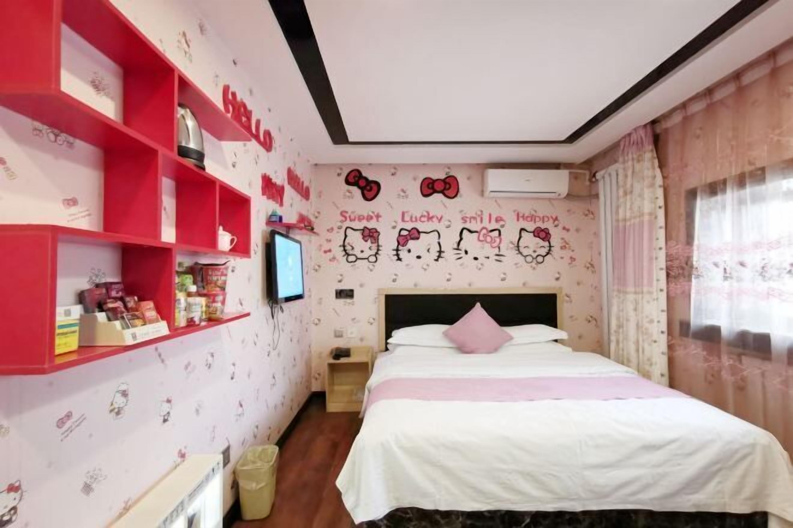 A bedroom with a bed, a TV, a shelf with items, and a wall with Hello Kitty decorations.