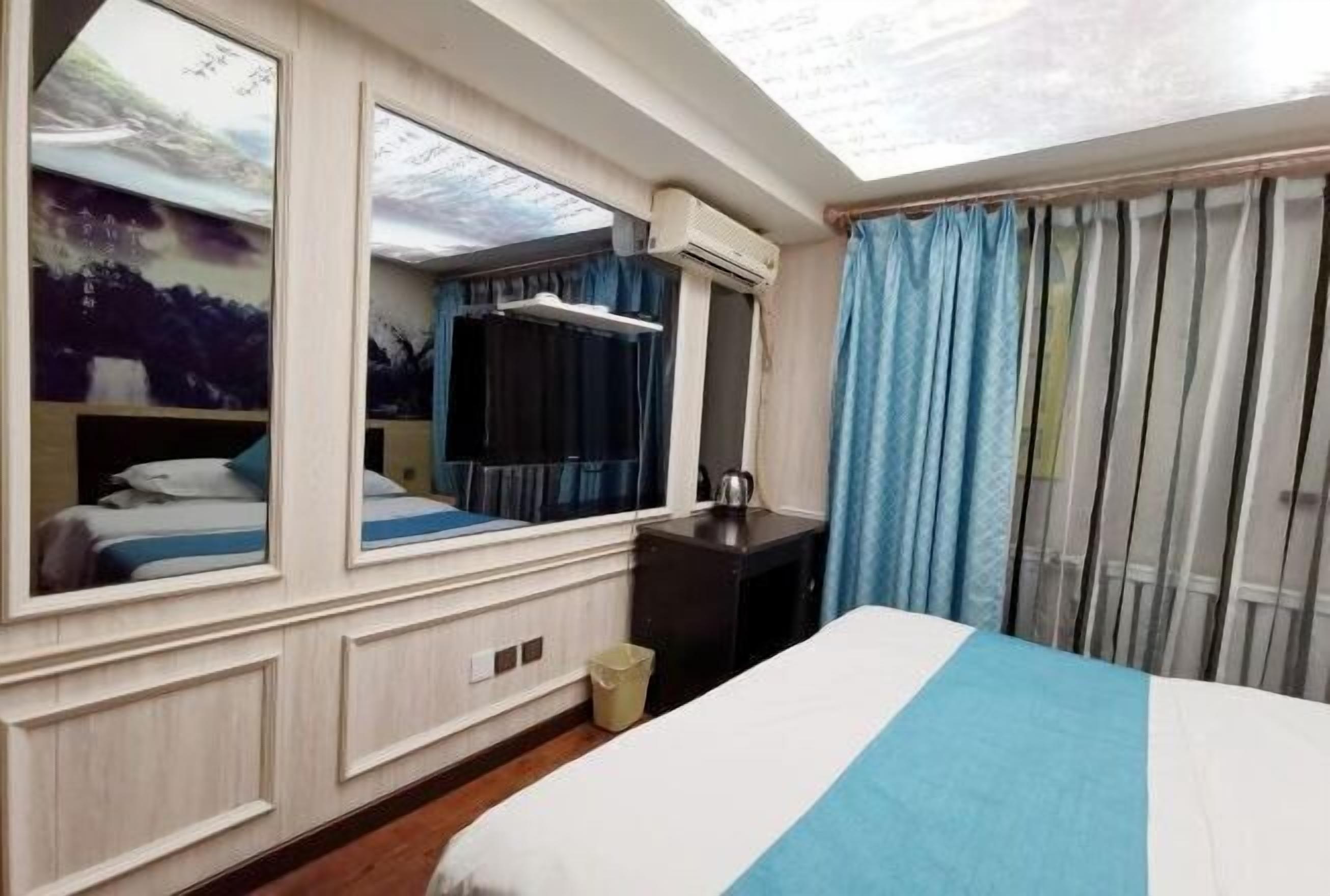 Una habitación de hotel con una cama grande, un escritorio, un espejo y una ventana con cortinas.