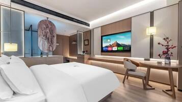 Une chambre d’hôtel moderne équipée d’un grand lit, d’un bureau, d’une télévision et d’un coin salon.