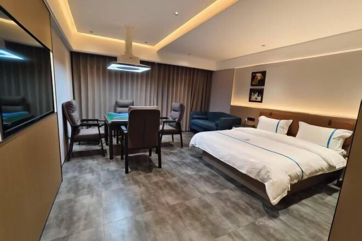 Een moderne hotelkamer met een groot bed, een bureau met stoelen, een bank en een televisie.