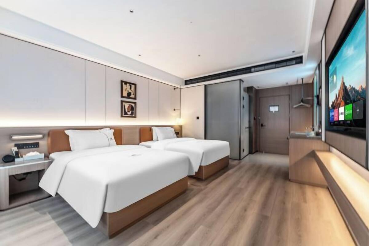 Een moderne hotelkamer met twee bedden, een bureau, een televisie en een kledingkast.