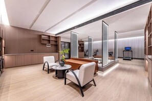 Eine moderne Hotelhalle mit Sitzgelegenheit, einer Rezeption und einem großen Spiegel.