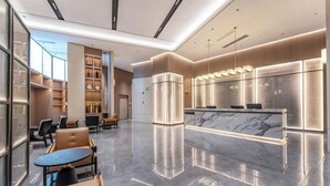 Een moderne lobby met een marmeren receptiebalie, een zithoek en een glazen wand met uitzicht.