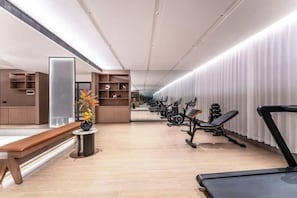A gym with exercise equipment, benches, and a wooden floor.