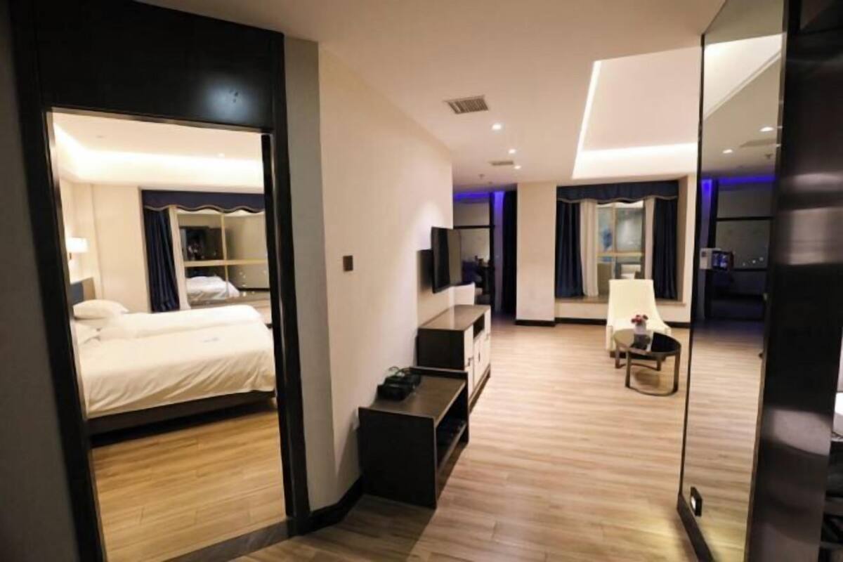Een moderne hotelkamer met een bed, bureau, stoel en spiegel.