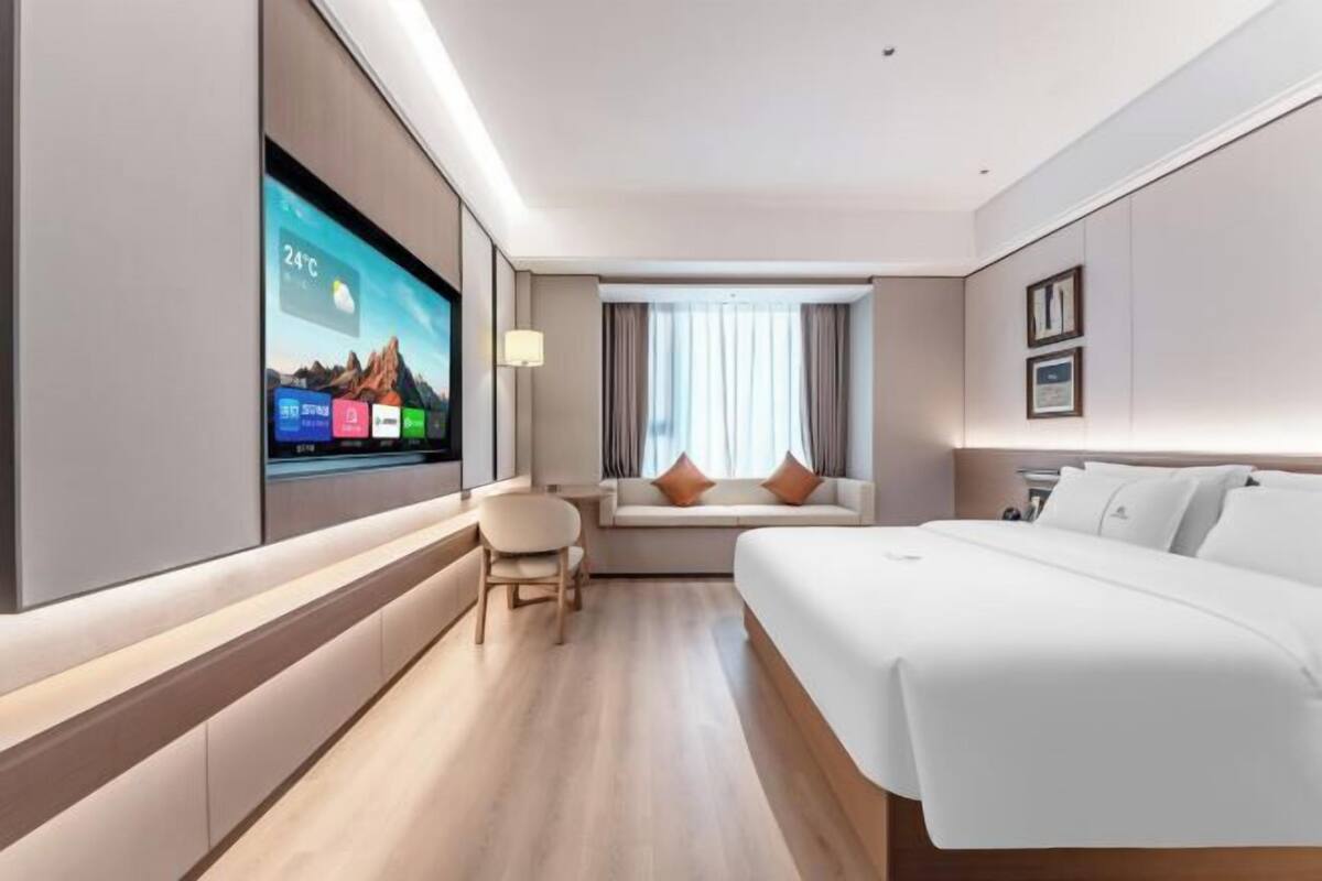 Een moderne hotelkamer met een groot flatscreen televisietoestel, een slaapbank, een bureau en een ruim bed.