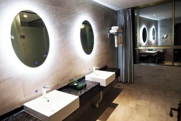 Une salle de bain moderne avec deux lavabos, un grand miroir et un meuble-lavabo doté d’un porte-serviettes.