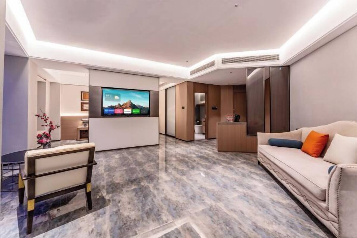 Een moderne hotelkamer met een flatscreen televisie, een bank, een stoel en een klein tafeltje.