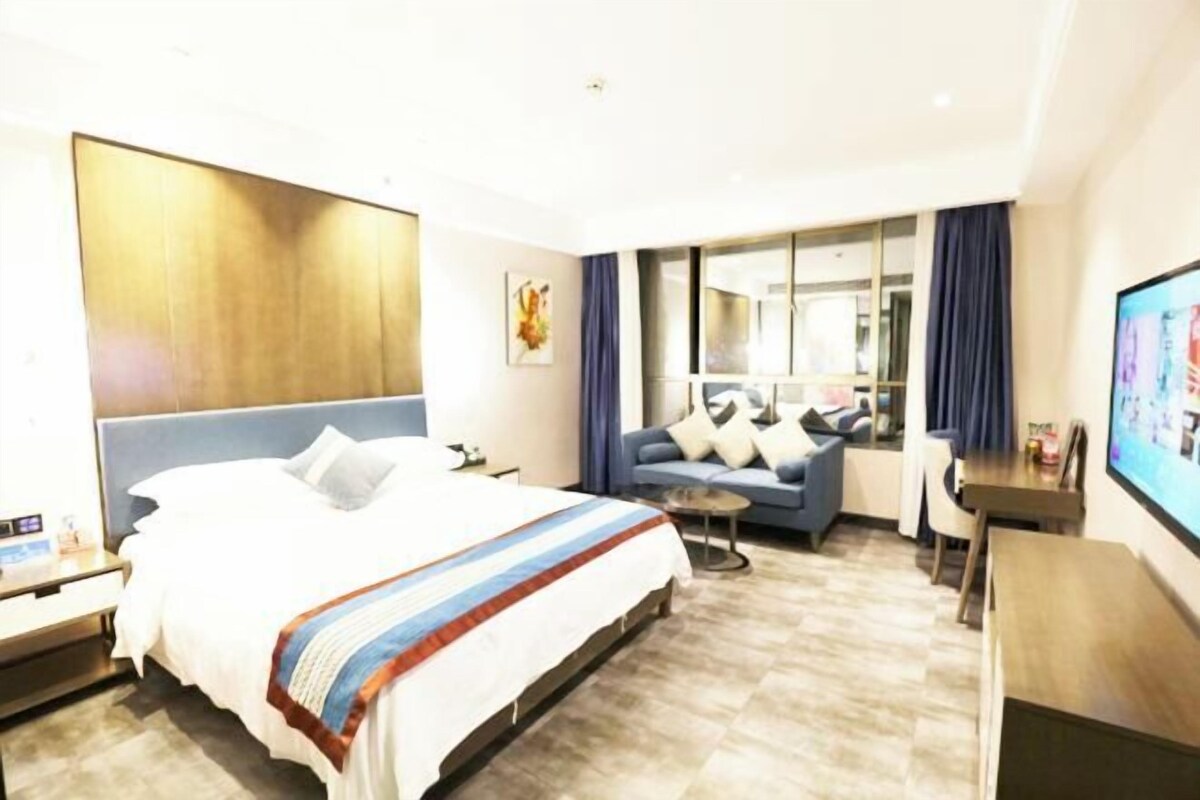 Une chambre d’hôtel avec un grand lit, un canapé, une télévision et un bureau.
