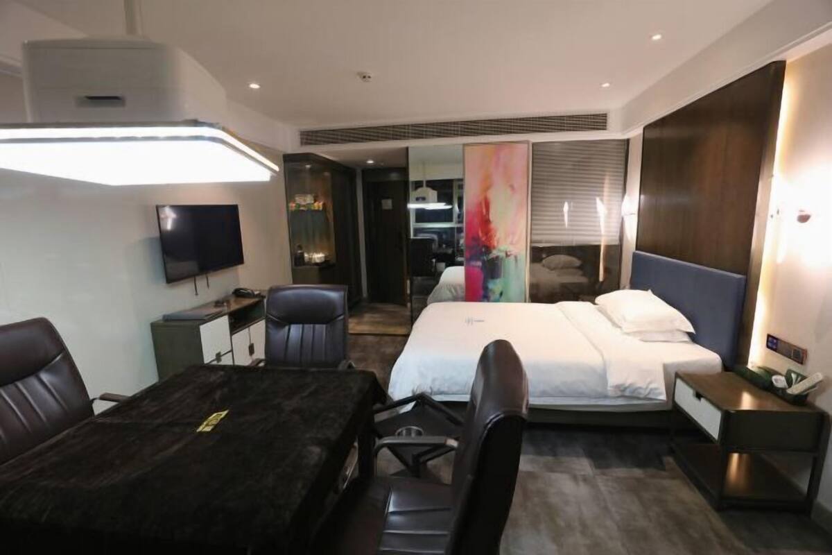 Een moderne hotelkamer met een bed, een bureau, een stoel, een televisie en een groot raam.