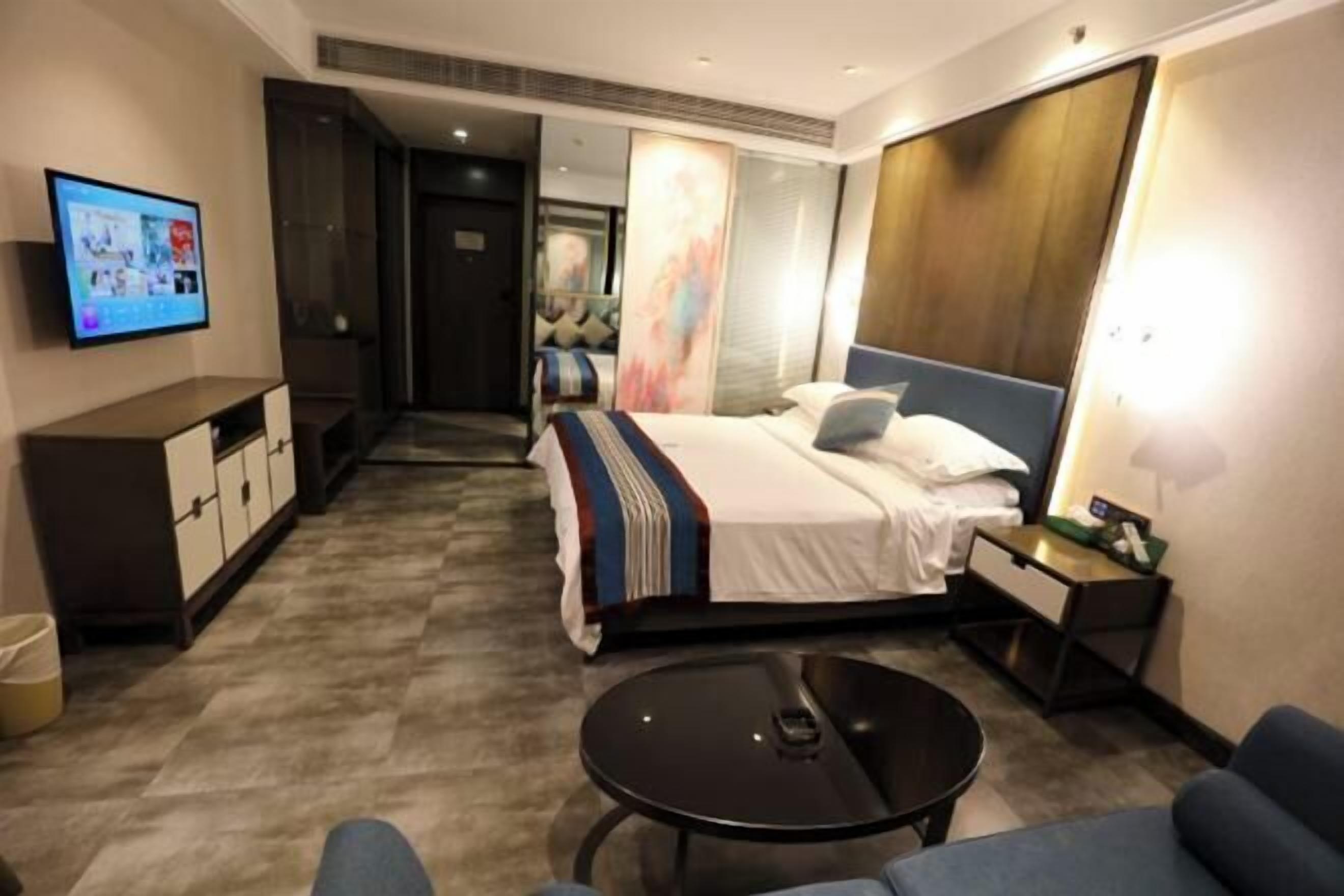 Une chambre d’hôtel moderne équipée d’un lit, d’une table de chevet, d’une télévision et d’une petite table ronde.