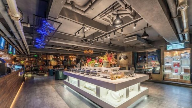 Een modern interieur met een centraal eilandpresentatie, blootgelegd buizenwerk en een bar voorzien van digitale schermen.