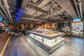 Een modern interieur met een centraal eilandpresentatie, blootgelegd buizenwerk en een bar voorzien van digitale schermen.