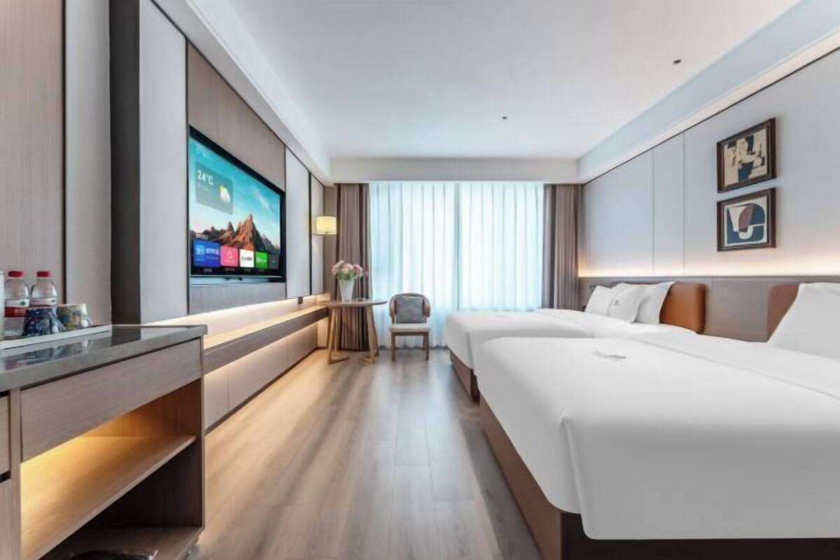 Een hotelkamer met een groot flatscreen televisietoestel, een bed, een bureau en een stoel.