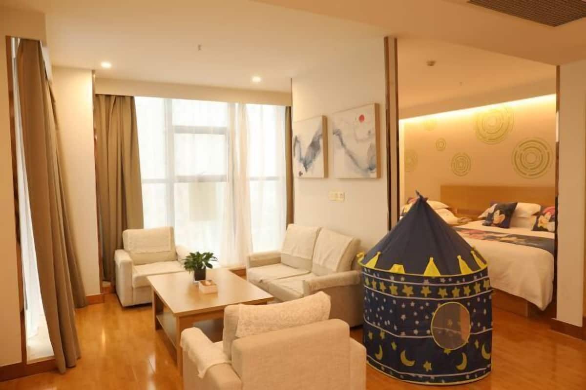 Una habitación de hotel con una cama, una pequeña tienda de juegos, un sofá y una mesita de café.