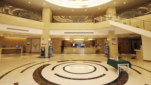 A spacious lobby with a central circular design, a reception desk, and a staircase connecting floors.