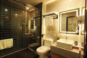 A modern bathroom with a glass-enclosed shower, a toilet, a sink with a mirror, and a towel rack.