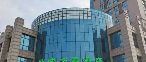 A modern hotel with a curved glass facade and a sign in a foreign language.