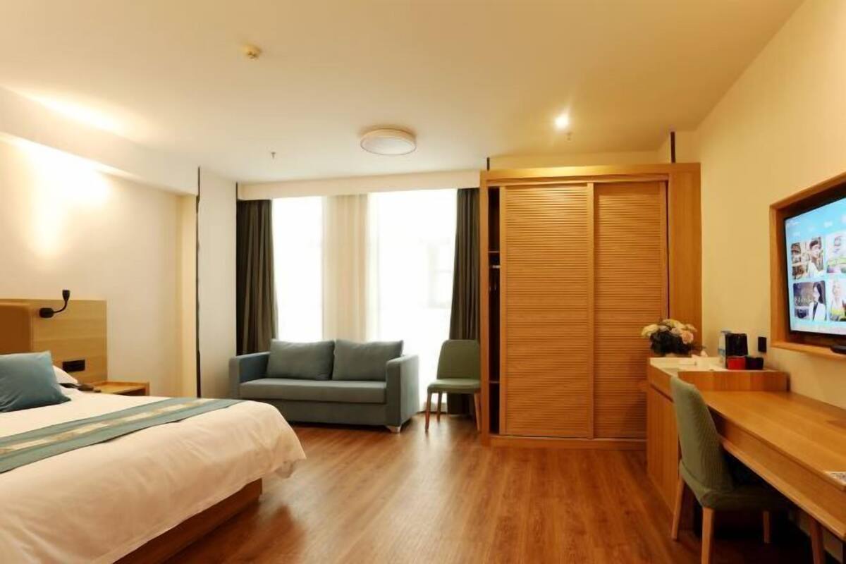 Habitación de hotel con una cama, un sofá, un escritorio y un televisor.