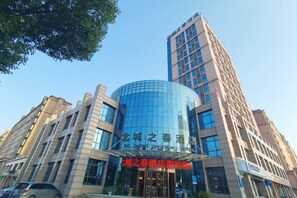 A modern building with a curved glass facade and a traditional rectangular structure. - Bei Cheng Zhi Chun Hotel (Jingmen)