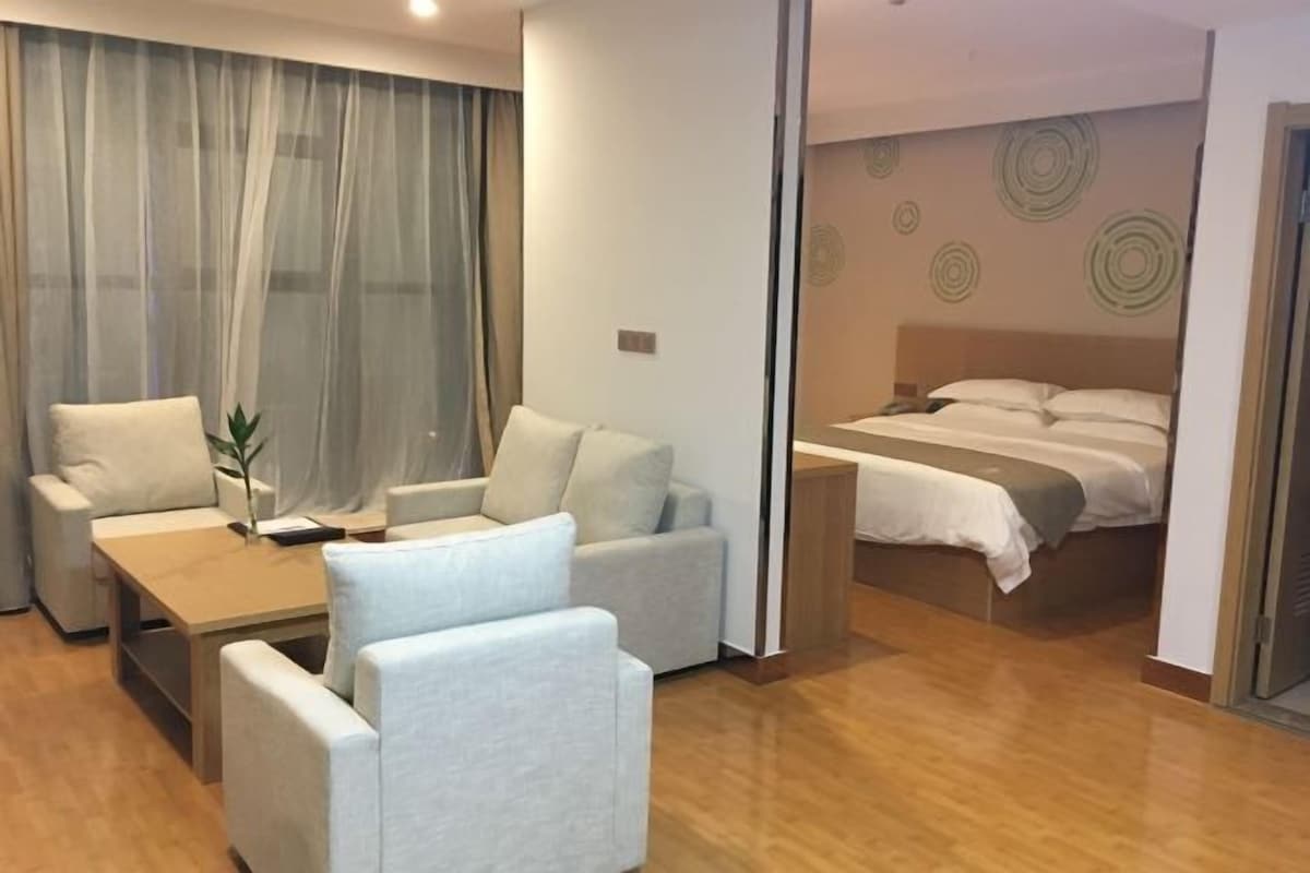 Quarto de hotel com cama, sofá, mesa pequena e uma cadeira.