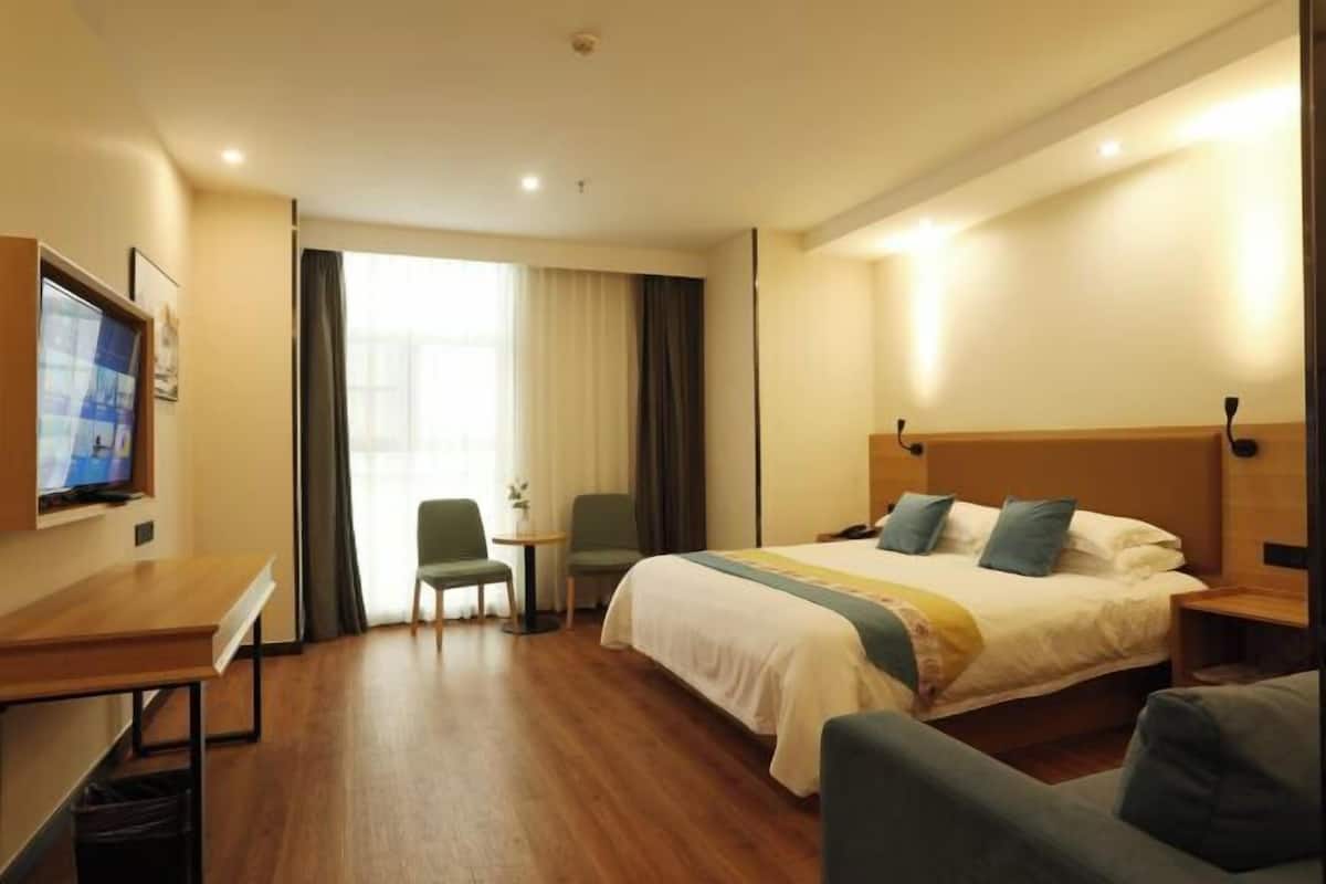 Una habitación de hotel con cama, escritorio, silla y televisor.