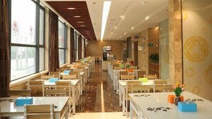 A hotel lobby with rows of tables and chairs, large windows, and a modern interior design.