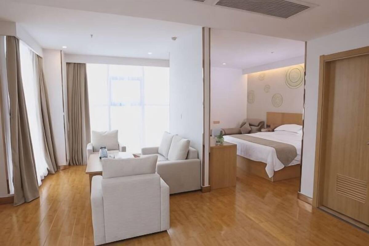 Una habitación de hotel con cama, sofá, mesita de noche y ventana.
